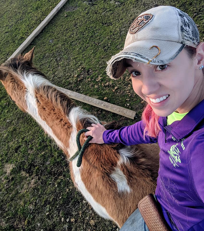 Jessica Shively in purple shirt and baseball cap riding her paint horse Rocket bareback.