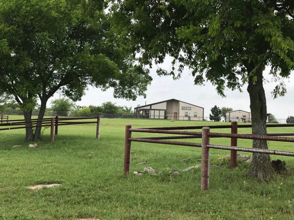 Barndominium framed by beautiful trees and green pasture.