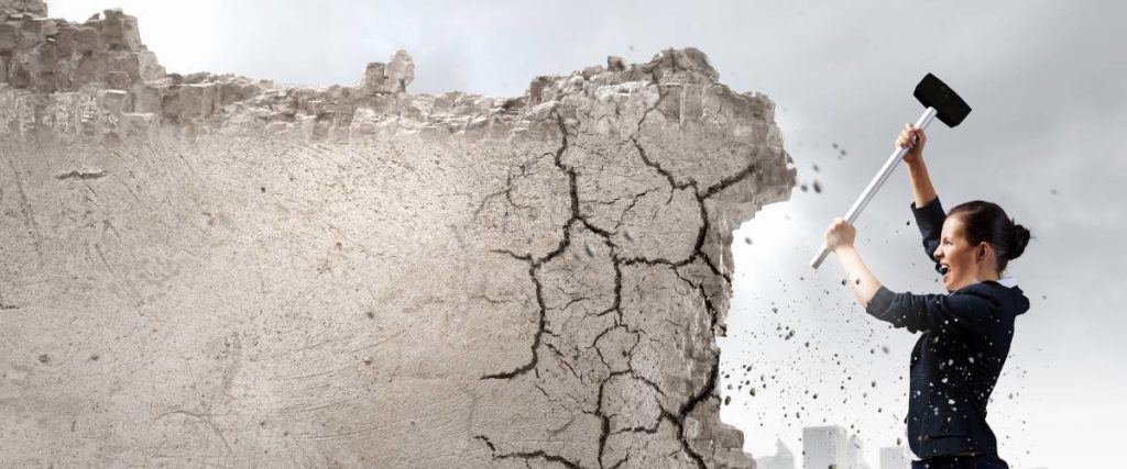 woman with sledge hammer breaking down concrete wall