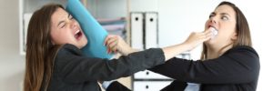 two young women in business attire in physical conflict with one another